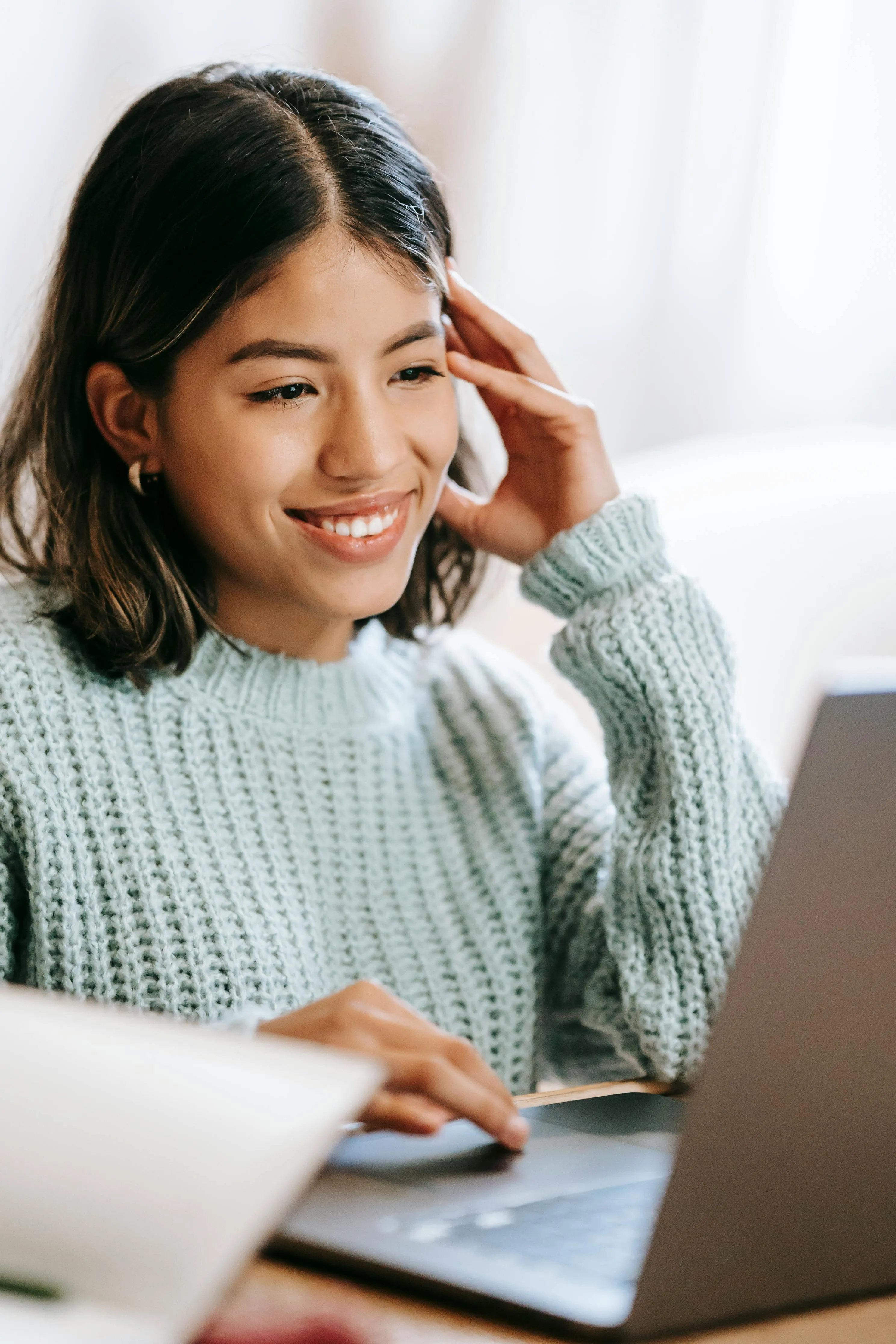 A young girl smiling while facing her laptop